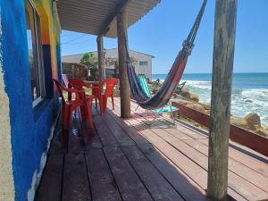 阿加斯杜尔斯Amanecer en aguas dulces的一个带椅子和吊床的门廊和大海