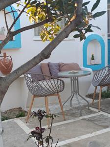 AgkidiaPERIVOLI 1-CHORA(5min away from the center by car)的庭院设有两把椅子和一张桌子,还有一棵树