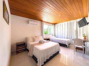 莫罗圣保罗Pousada Linda flor的酒店客房带两张床和一张桌子以及椅子。