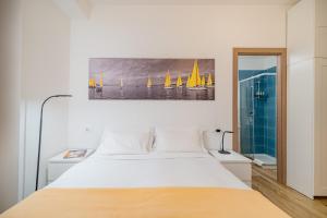 卡利亚里Residenze Asproni Serviced Apartments的卧室配有白色的床和墙上的绘画作品
