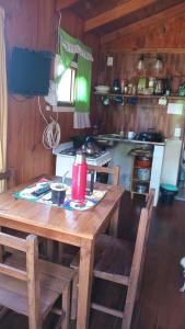 Puerto BossettiCabañas Aliwen的厨房配有木桌、椅子和炉灶