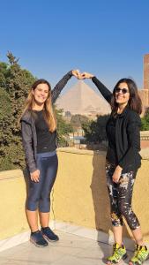开罗Ramses Guest House的两个女人站在金字塔前