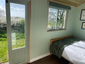 盖尔文Cosy Shepherd Huts near Newborough Forest Anglesey的一间卧室设有一张床和一个窗口