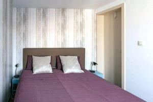 布兰肯贝赫Edelweis的一间卧室配有一张带两个枕头的紫色床