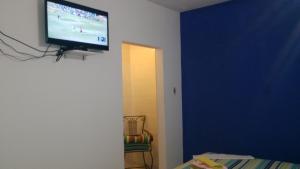 Luque住客旅馆的客房内的蓝色墙壁上设有平面电视