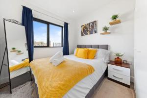 赫默尔亨普斯特德OCEAN BLUEZ 1bdr city centre的一间卧室配有一张带黄色枕头的床和一扇窗户