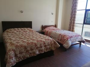苏克雷Apartamentos MI FAMILIA的一间卧室设有两张床和窗户。