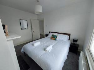 伦敦Large Serene Victorian Abode in Central London的卧室配有白色的床和2条毛巾