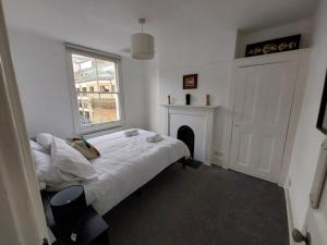 伦敦Large Serene Victorian Abode in Central London的一间白色卧室,配有一张床和一个壁炉