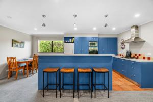 哈威亚湖Hāwea Delight - Lake Hāwea Holiday Home的厨房配有蓝色橱柜和酒吧凳子