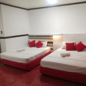Lapu Lapu CityMax Travellers Inn的两张位于酒店客房的床铺,配有红色枕头