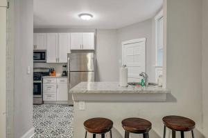 Clifton HeightsBeautiful Brand New Tower Grove Unit 1s的厨房配有白色橱柜和带凳子的台面