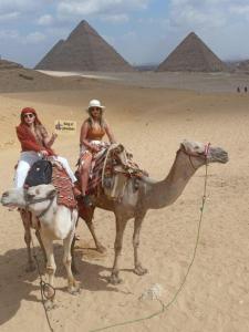 开罗king of pharaohs pyramids view的两个女人骑在金字塔里的骆驼上