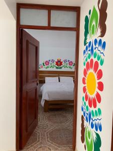 阿亚库乔PERLASCHALLAY的卧室配有一张挂着花壁画的床。