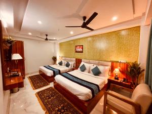 哈里瓦The Tirath Palace Luxury Hotel In Haridwar的一间卧室配有两张床和吊扇