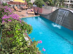 尼甘布Beach Corridor Hotel & Spa的一座带瀑布和紫色鲜花的游泳池