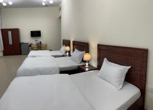 阿吉曼Family rooms with beach view يستضيف مكان الإقامة هذا العائلات فقط的酒店客房设有三张床和电视。