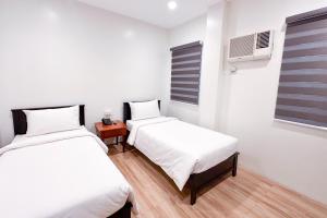 马尼拉SANTOS Pension House的一间卧室设有两张床和窗户。