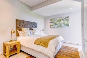 巴利托Oceans Edge 4, Zimbali Estate的白色卧室设有一张带木制床头板的大床