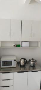 汝来Camelia Youth City Nilai Studio residence 5pax的厨房配有白色橱柜和微波炉