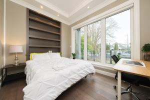 温哥华Dunbar Luxury Homestay的一间卧室配有一张床、一张书桌和一个窗户。