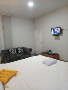 纳闽巴霍La Geiro Villa Labuan Bajo的卧室配有白色的床和平面电视。