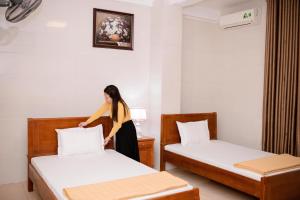 荣市Thảo Nguyên Hotel的女人站在房间里两张床之间