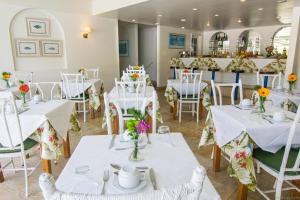 布希奥斯杜斯玛尔酒店的餐厅设有白色的桌椅和鲜花