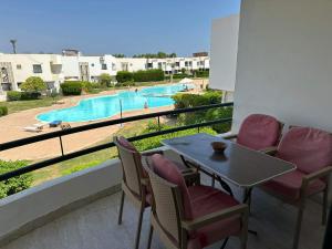 沙姆沙伊赫Criss Resort- Namaa Bay- Middle of Sharm的一个带桌椅的阳台和一个游泳池