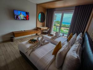 龙目岛库塔Raja Hotel Kuta Mandalika Resort & Convention的酒店客房设有两张床和大窗户。