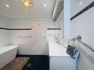 悉尼Maroubra Gem Close to Everything Sleep 16的白色的浴室设有浴缸和水槽。