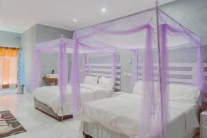 MangochiAdams lodges Ltd的一间卧室配有两张紫色窗帘的床