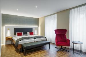 因特拉肯Hotel Du Nord的一间卧室配有一张床和一张红色椅子
