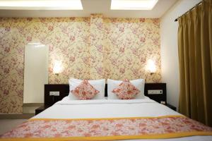 西里古里Voyage Comfort Primer Inn的一间卧室配有一张带花卉壁纸的大床