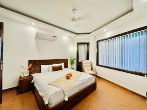 新德里BedChambers Serviced Apartments South Extension的卧室配有床、椅子和窗户。