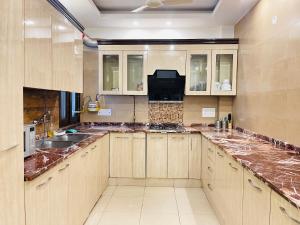 新德里BedChambers Serviced Apartments South Extension的一个带木制橱柜和大理石台面的大厨房