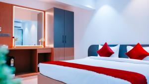 孟买Hsquare Hotel Andheri West的一间卧室配有一张带红色枕头和镜子的床