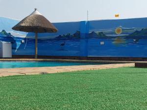 MkuzeMKHUZE INN的一个带遮阳伞和壁画的游泳池