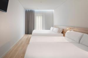 奥良B&B HOTEL Olhão Algarve的配有白色墙壁和木地板的客房内的两张床