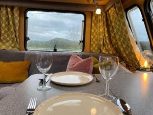 Hulme EndCosy Caravan on Luxury Campsite的一张桌子,上面放有盘子和酒杯,放在火车上