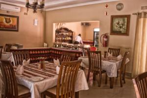 卢萨卡Waterfalls hotel (Lusaka)的一间设有桌椅的餐厅,以及一位背景人士