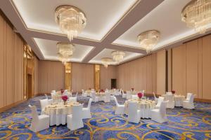 博帕尔博帕尔万怡酒店 的宴会厅配有白色的桌椅和吊灯。