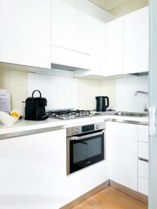 阿斯蒂ComeCasa San Secondo White的厨房配有白色橱柜和炉灶烤箱。