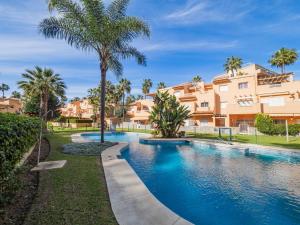 马贝拉Cubo's Cabopino Beach Marbella Apartment的一座楼前棕榈树游泳池