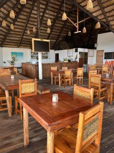 托弗海滩Mango Beach Resort的餐厅设有木桌、椅子和平面电视。