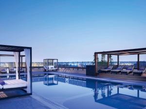 迪拜普尔曼迪拜河城市中心酒店的一座建筑物屋顶上带躺椅的游泳池