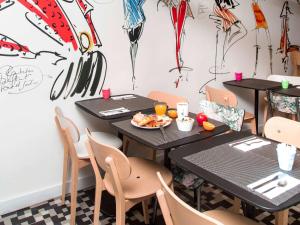 巴黎巴黎盖尔圣拉扎尔宜必思尚品酒店的餐厅设有2张桌子和椅子,提供一盘食物