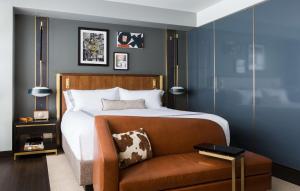 达拉斯Thompson Dallas, by Hyatt的一间卧室配有一张床和一张棕色椅子