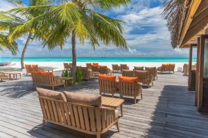 迪弗西Meeru Maldives Resort Island的海滩上带桌椅的木制甲板