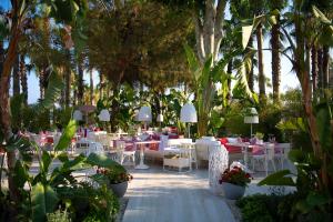 锡德Miramare Beach Hotel - Ultra All Inclusive的一间设有白色桌椅和树木的餐厅